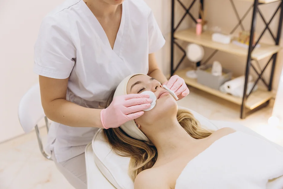 Aesthetician cleansing a client's face with cotton pads after a treatment
