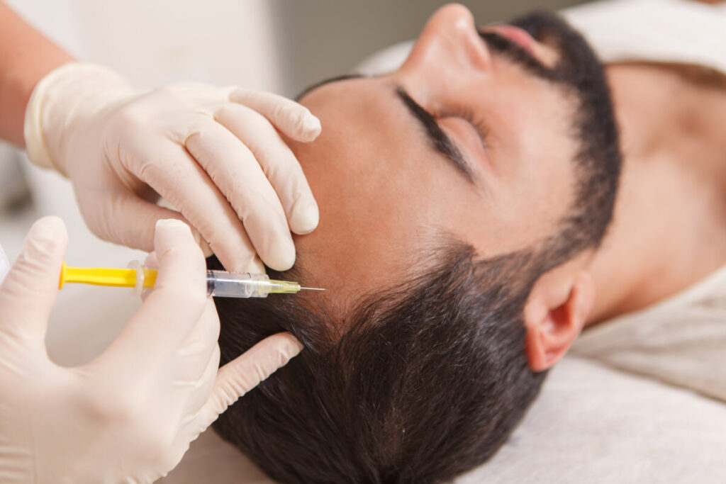 Close up of cosmetologist injecting vitamins in scalp of balding man