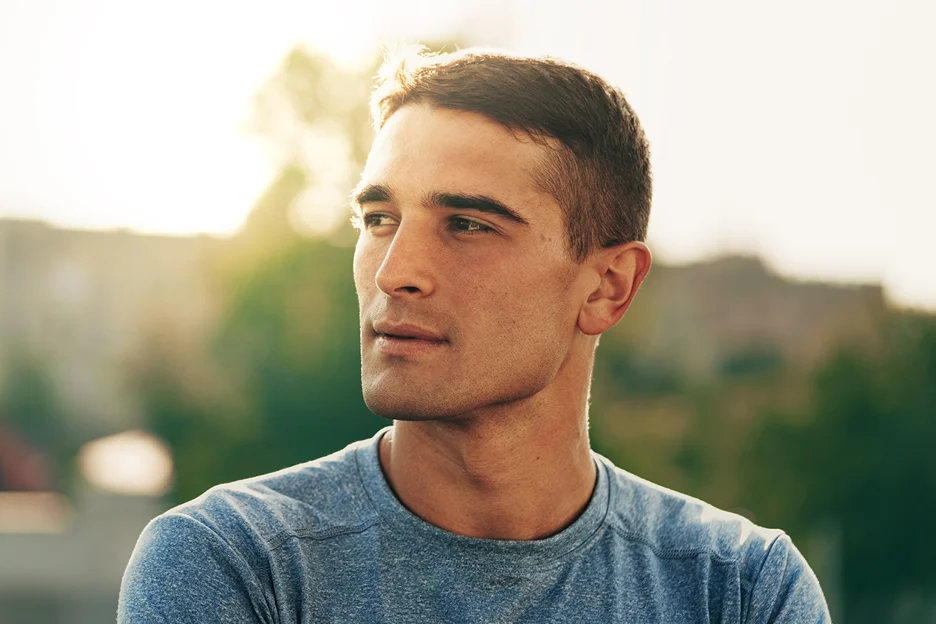 Man with clear skin looking to the side outdoors at sunset