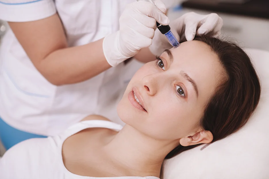 Practitioner in sterile gloves performing microneedling near a client's brow