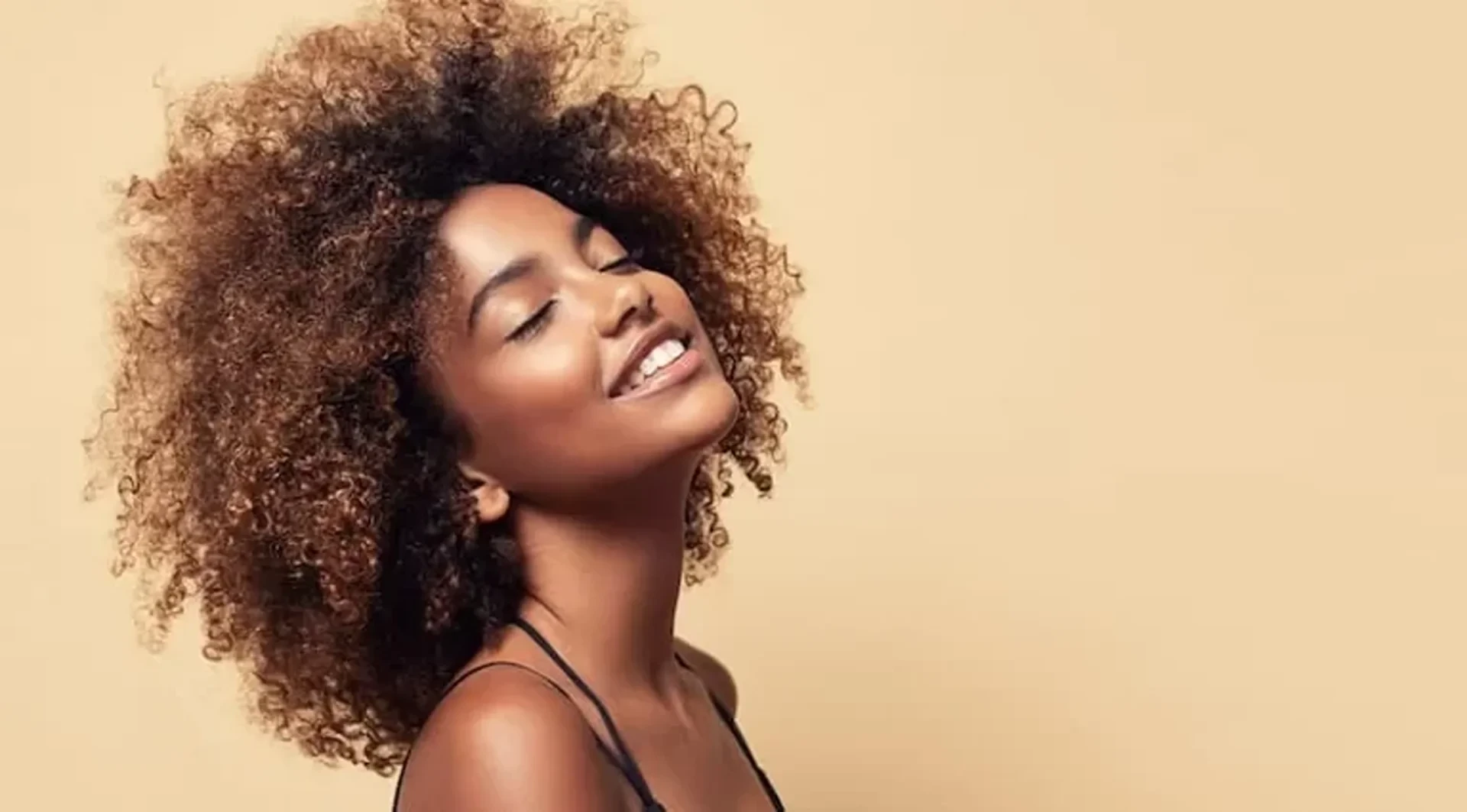 Natural dense afro hair on the head of the young beautiful model white toothy smile on her face