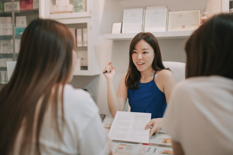 Asian chinese beautician explaining microneedling treatment to her customers