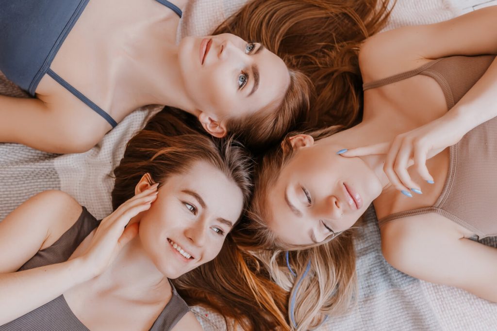 Girlfriends laugh at home lying on the floor on pillows