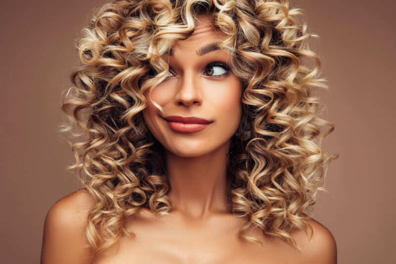 Studio portrait of attractive young woman with voluminous curly hairstyle