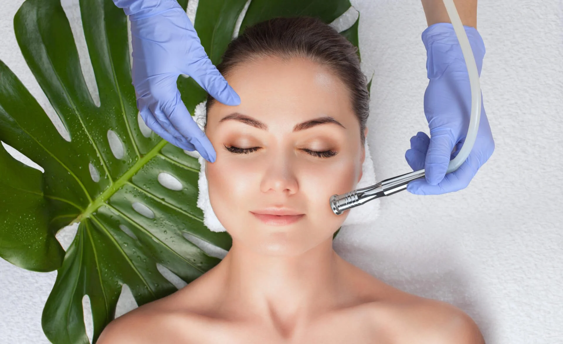 The cosmetologist makes the Microdermabrasion procedure of the facial skin of a woman