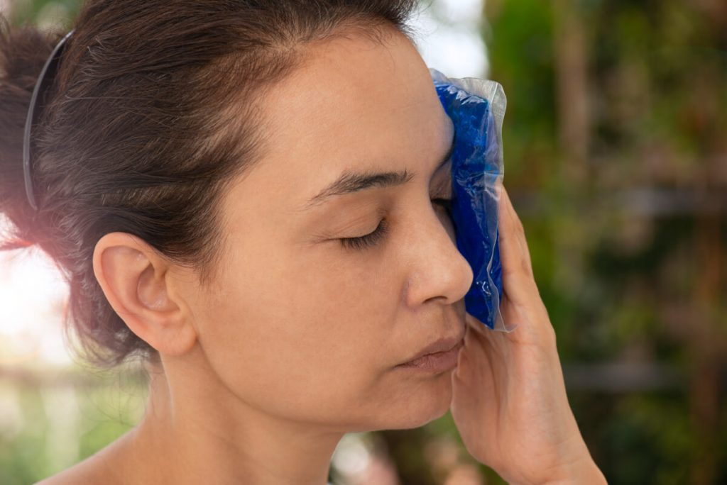 Woman holding gel pack on face.