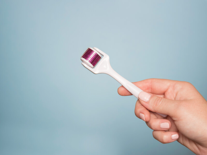 derma roller in hand on a blue background