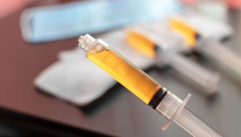 Blood plasma in a syringe on a blurred background