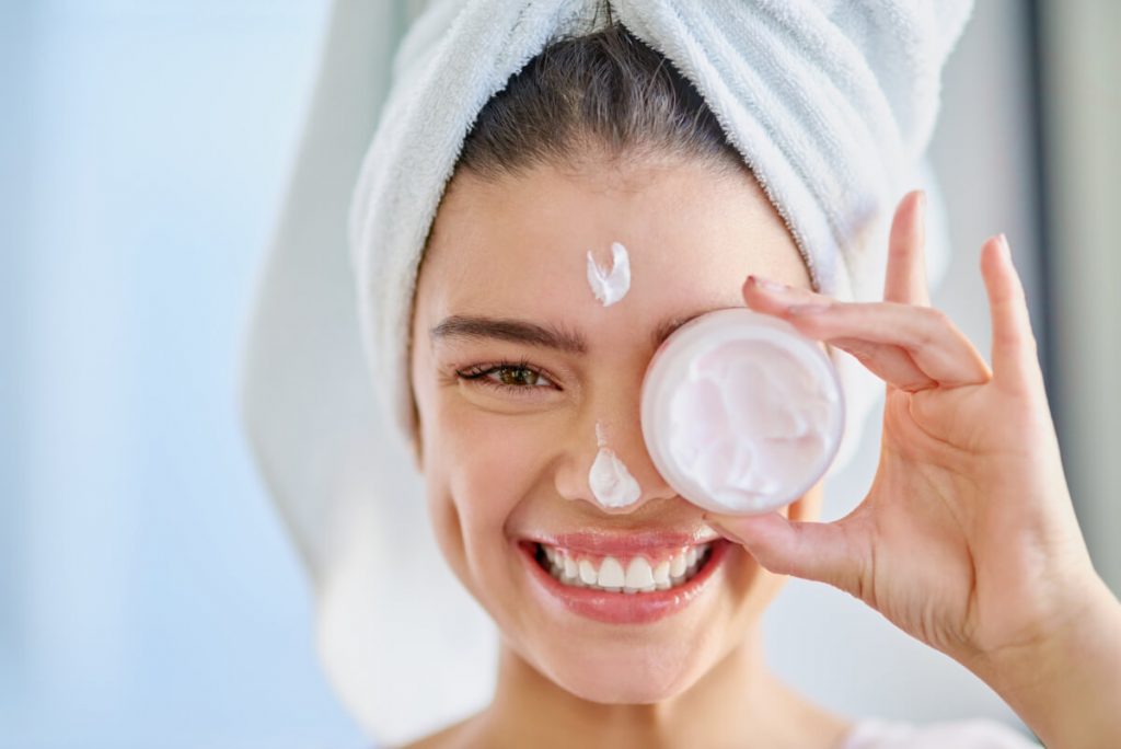 Cropped portrait of a beautiful young woman applying moisturizer to her skin in the bathroom