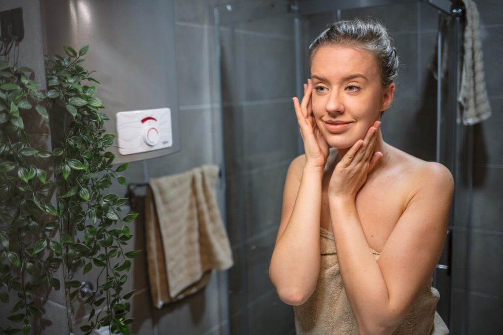 Happy woman admiring her skin in front of the bathroom