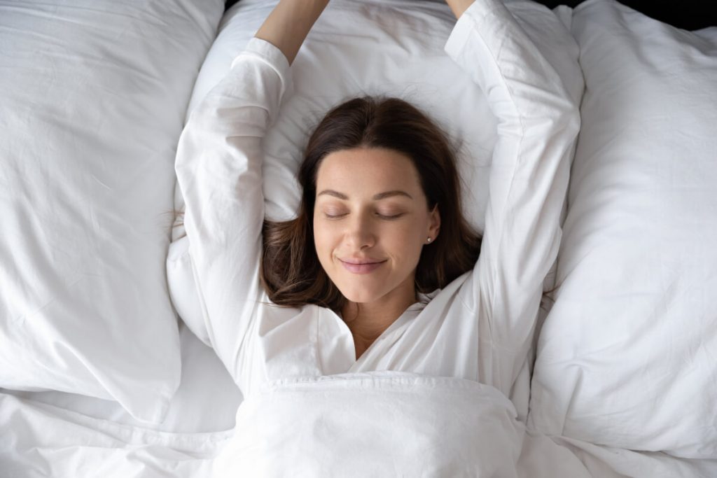 Top view young woman with closed eyes lying in pyjamas