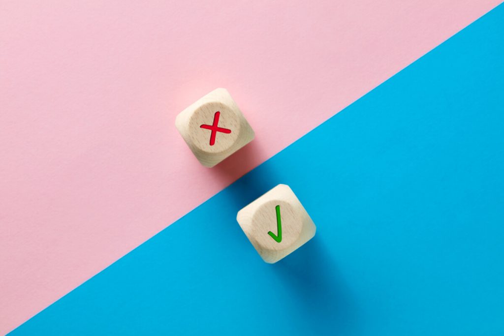 Wrong and right symbols on wooden cubes on pink and blue background
