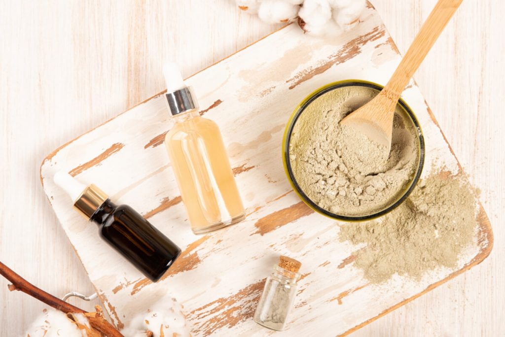 clay powder mask in a jar and beauty essence bottles