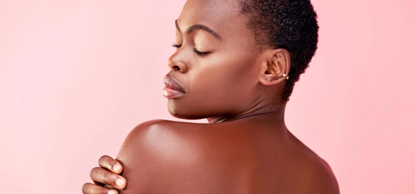 studio shot of a beautiful young woman posing against a pink background