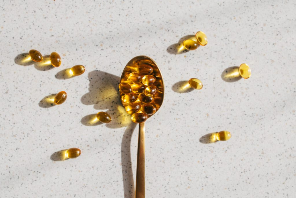 A high angle shot of a teaspoon full of vitamin D pills