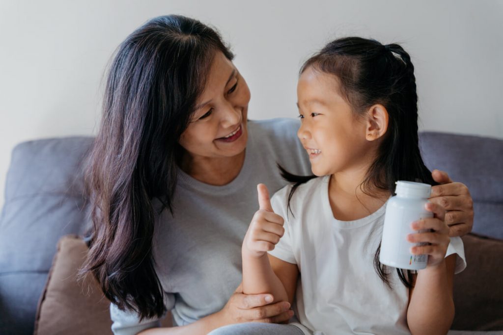 young asian girl ready to give supplement to her grandmother in living room