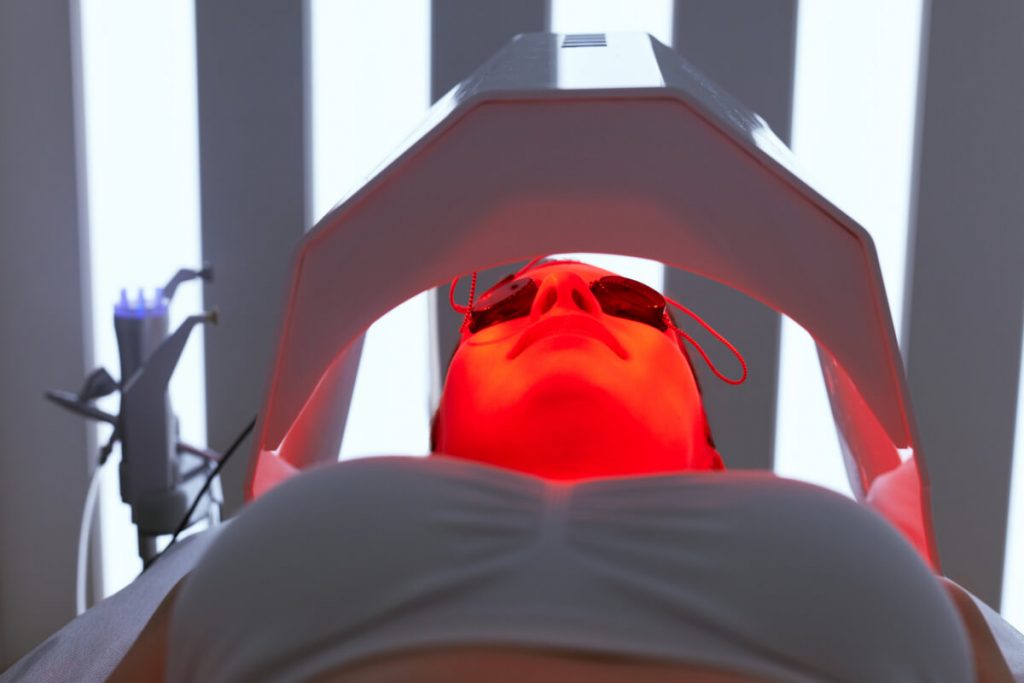 Woman Face At Red Light Treatment At Beauty Clinic