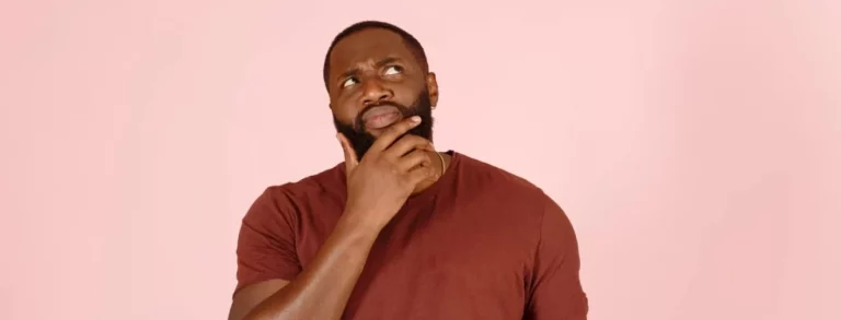 An afro American man touching his beard in pink background