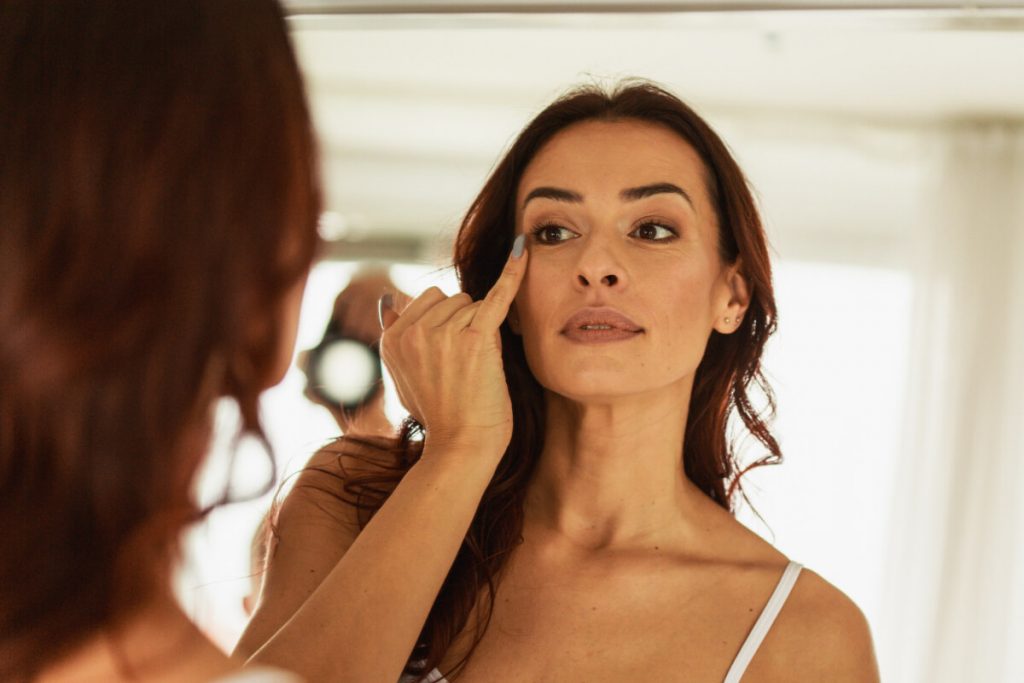 A woman looks in the mirror while touching her face