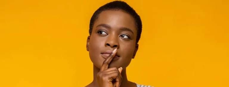 concentrated afro woman touching her lips while thinking