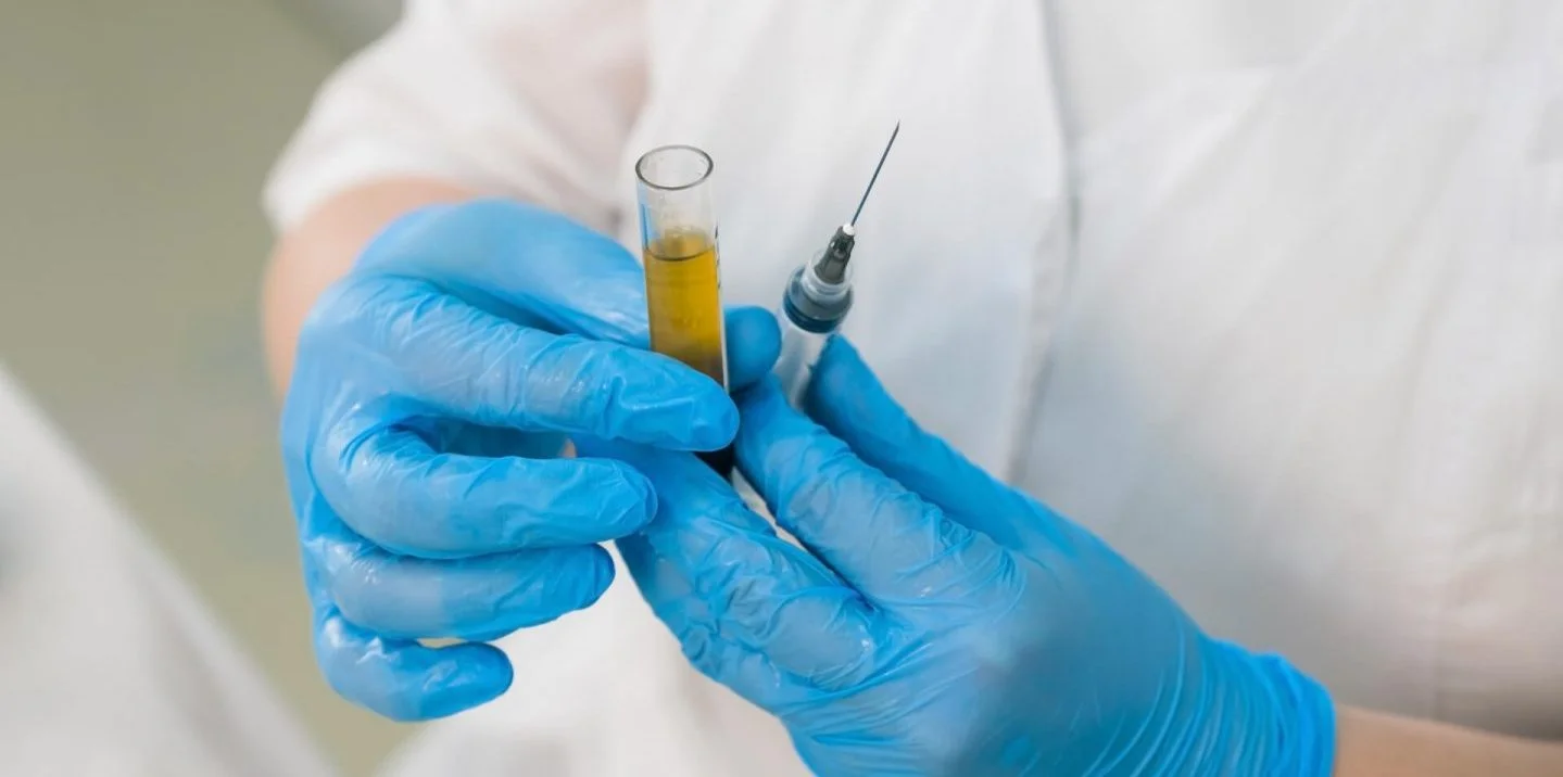 cosmetologist draws blood plasma into a syringe for prp treatment