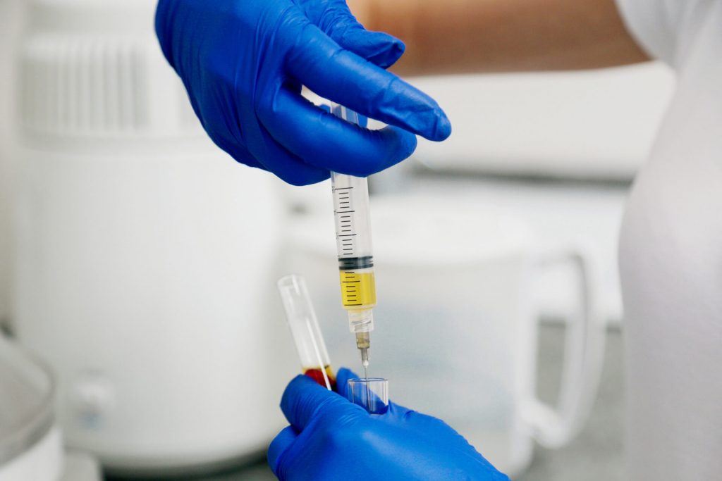 Doctor in blue gloves keep in hands test tube with a blood and plasma.