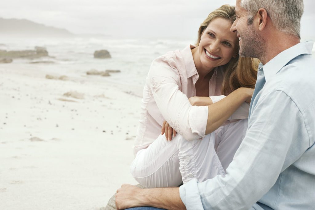 Happy loving couple sitting on beach