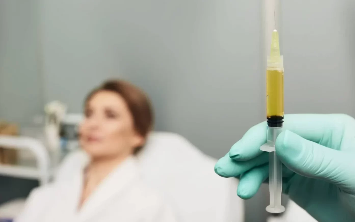 Syringe with a patient's blood plasma in a cosmetologist's hand