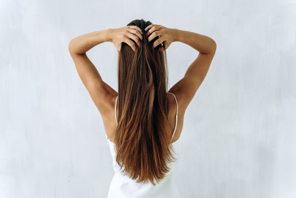 Waist up back side portrait of young brunette lady with straighten voluminous hair