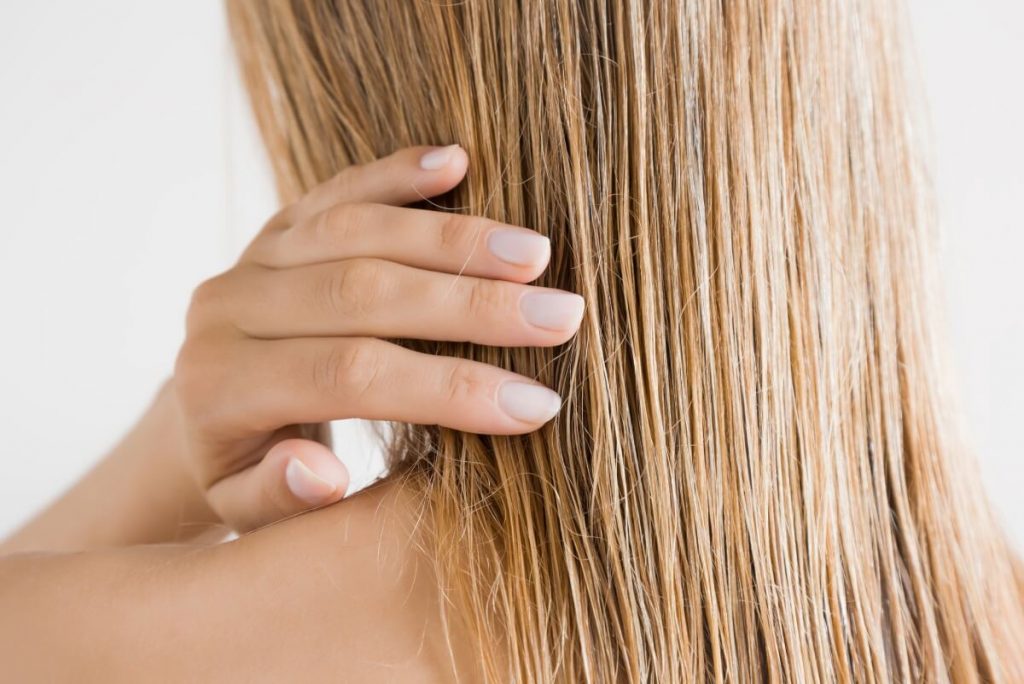 Young woman with hand touching her wet hair