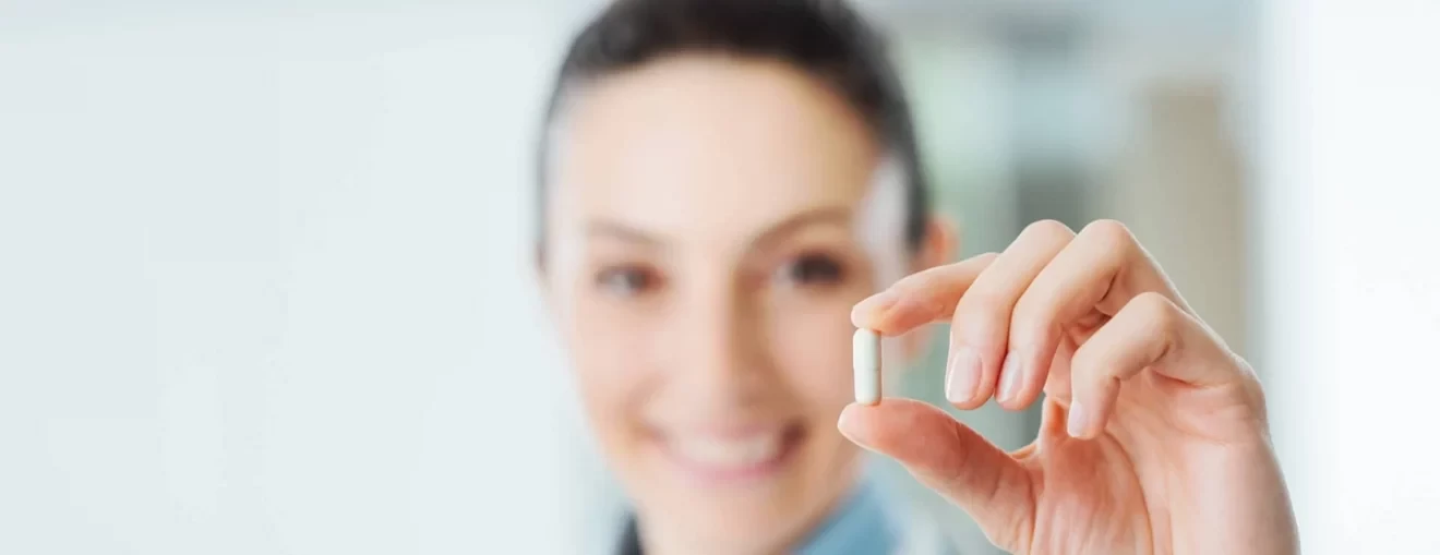 Smiling female pharmacist holding a pill