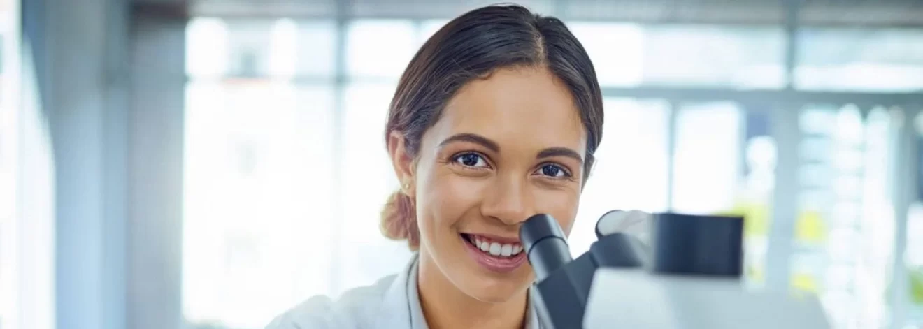 Portrait of a young scientist using a microscope in a lab