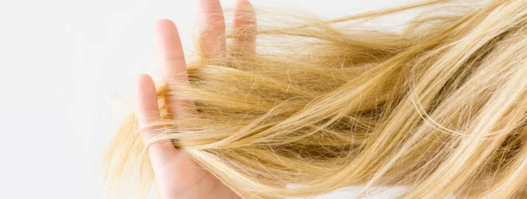 Woman's hand holding dry, blonde, tangled hair