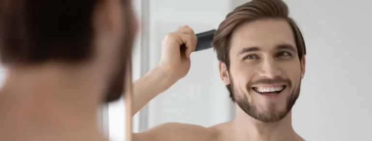 man combing smooth straight hair after PRP therapy, looking in mirror