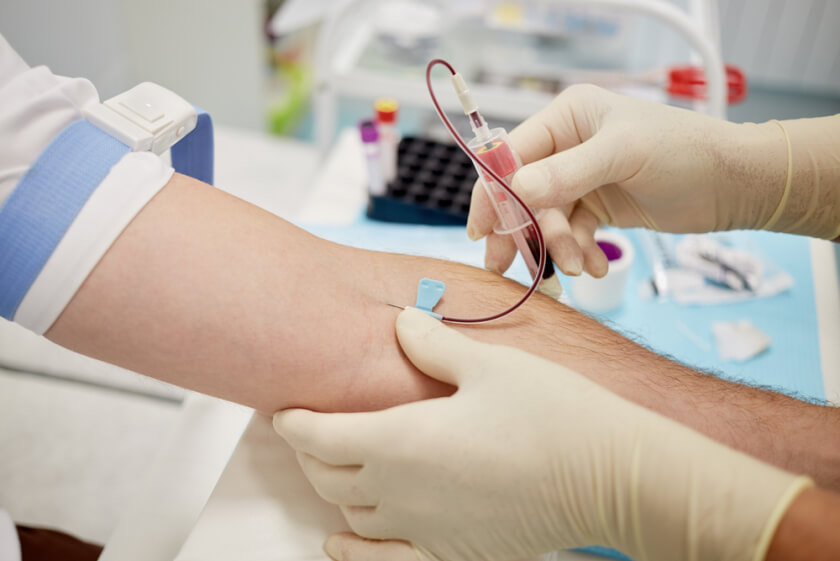 woman holds a tube and needle during drawing blood from man arm for prp treatment