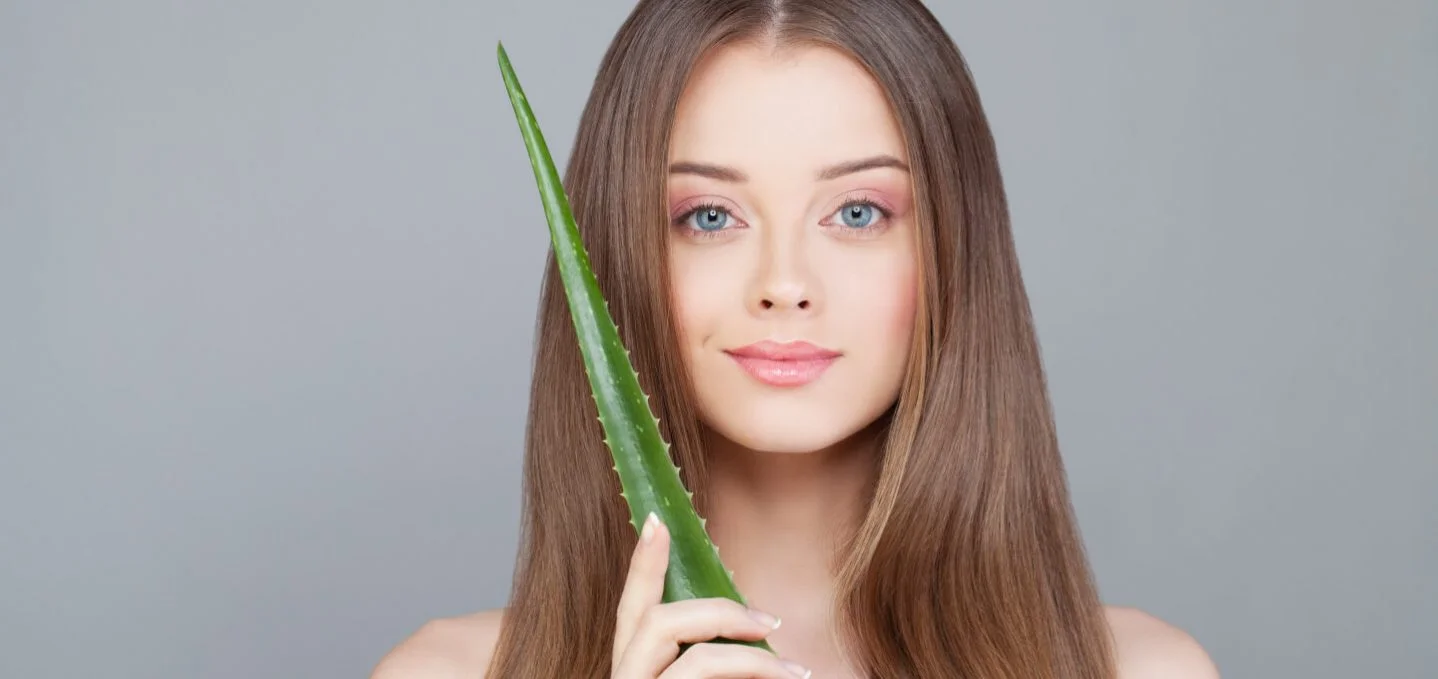 Woman after PRP hair treatment holding aloe vera leaf
