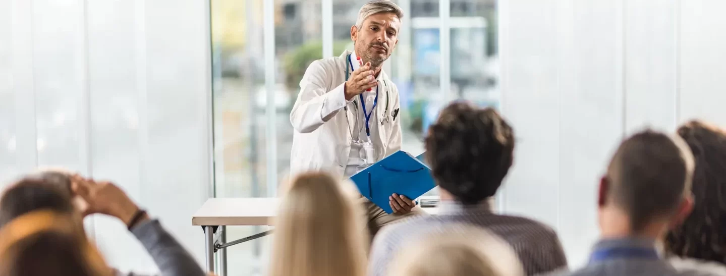Male doctor talking to large group of people on a training
