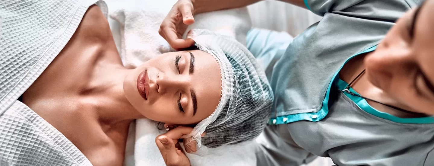 Woman lying on a medical couch and getting ready to receive aesthetics treatment.