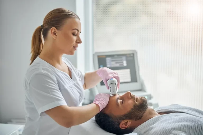 Charming female Esthetician treating male skin with laser device