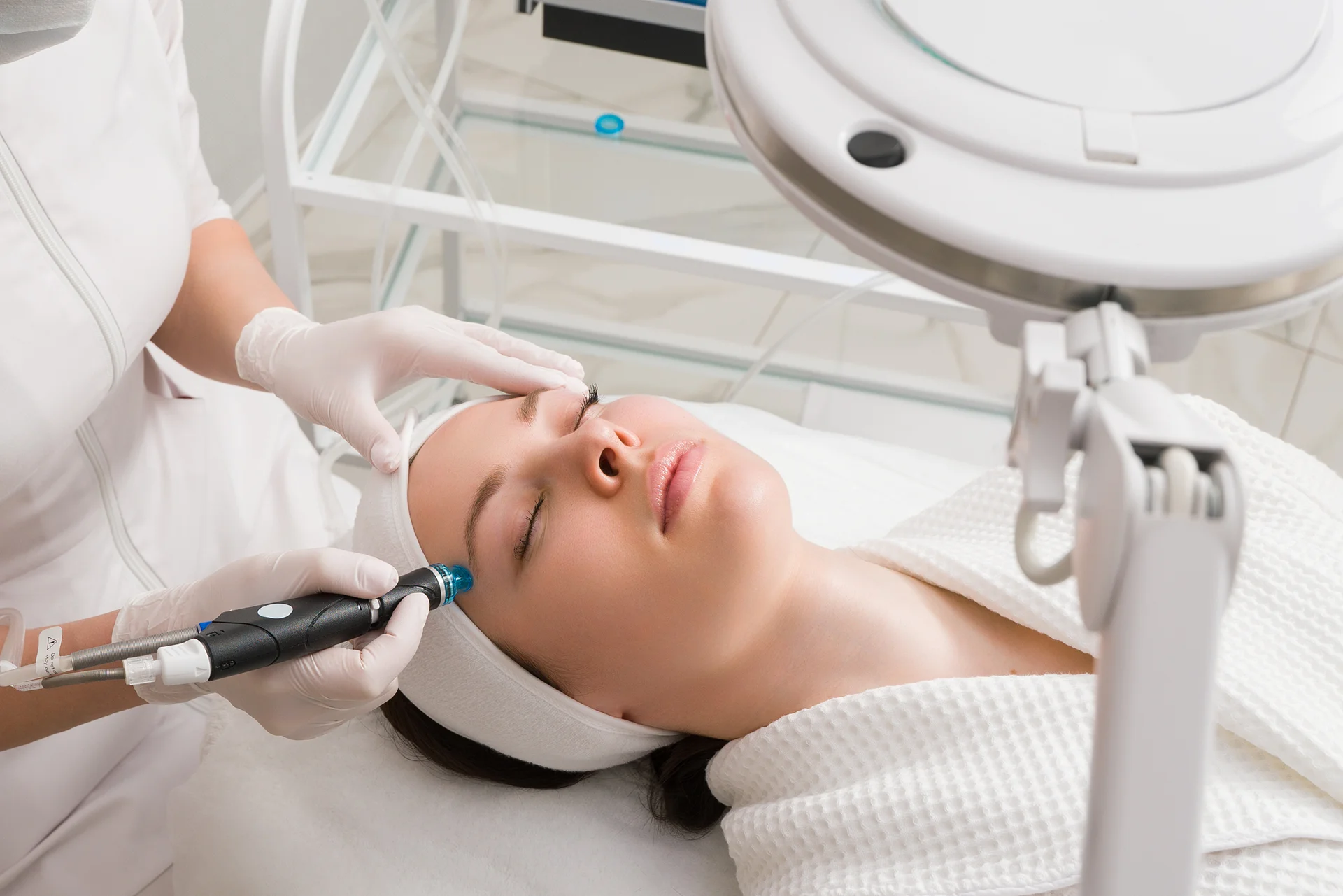 Medical esthetician performs Hydrafacial treatment on her patient