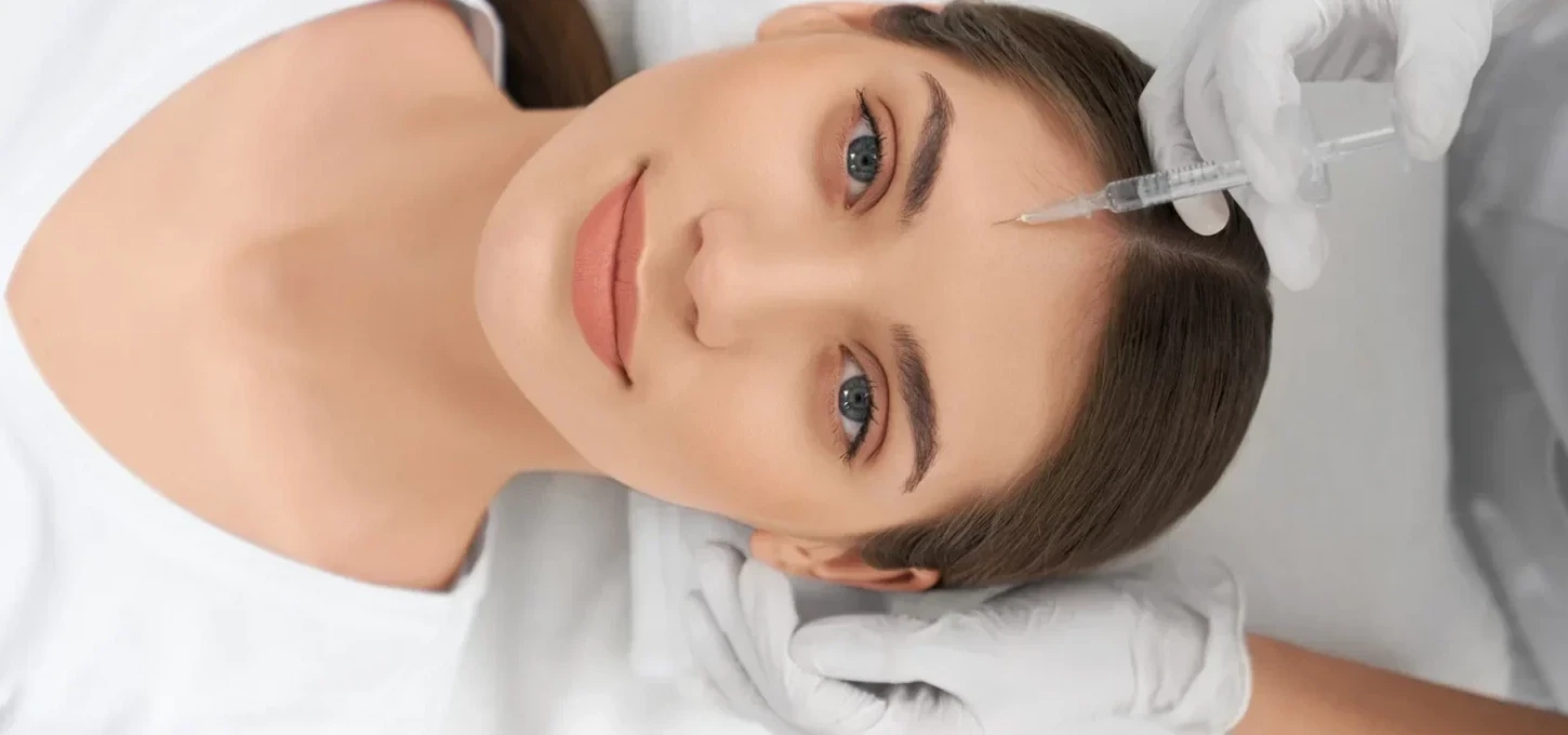 Top view portrait of cute young woman lying on procedure for face skin improvements thru injection anti-aging skin with professional cosmetics.