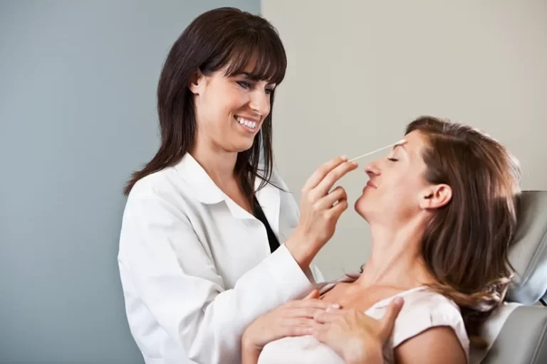 Esthetician performing treatment to a woman's face in clinic