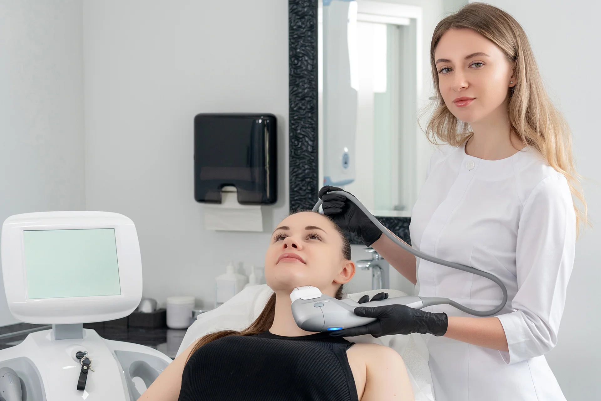 an aesthetician performs laser hair removal treatment to her client