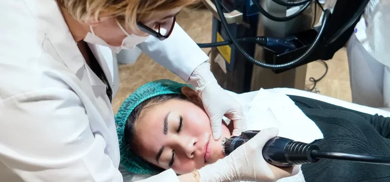 an aesthetician performs microneedling procedure on a client