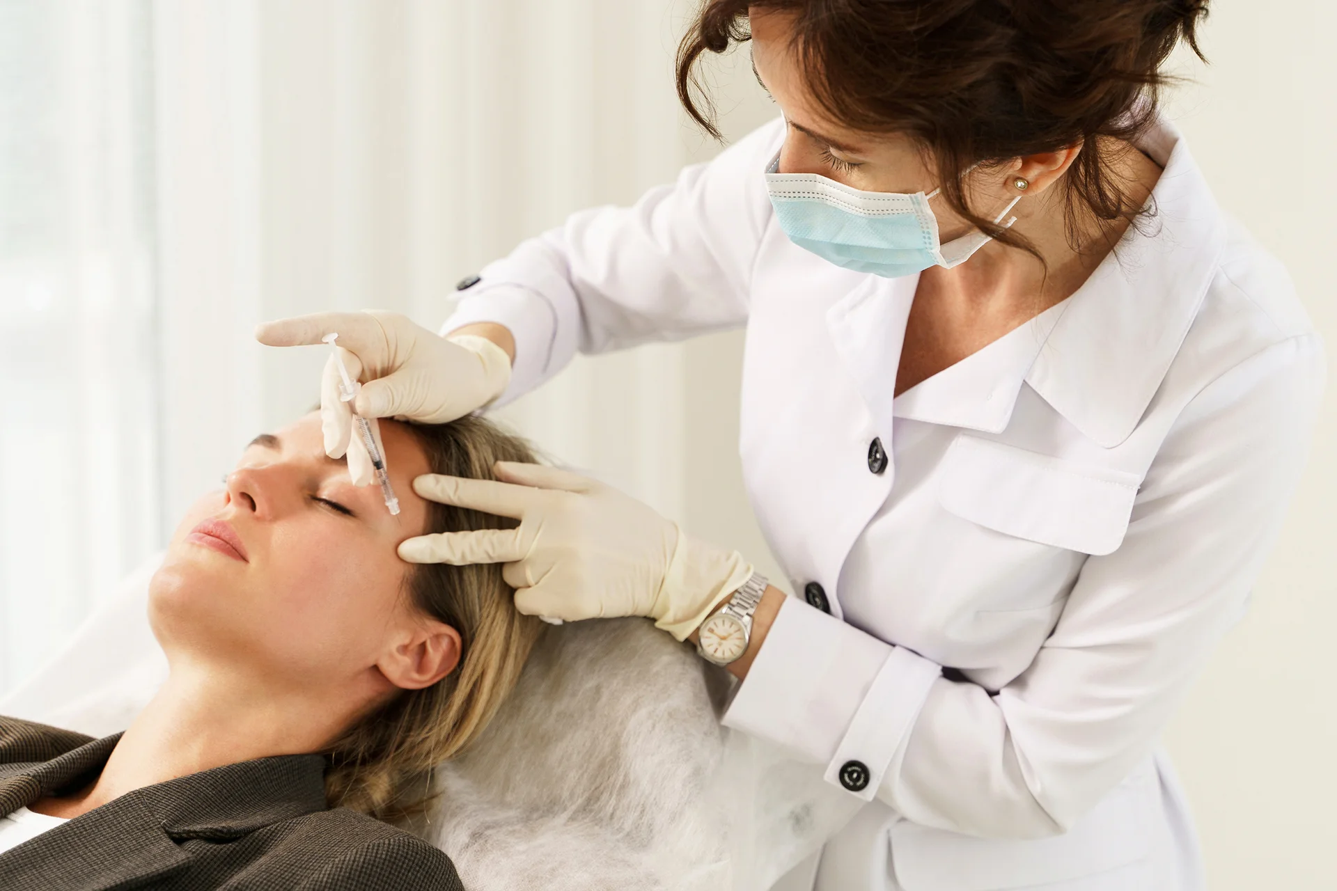 Medical esthetician gives botox treatment to her patient