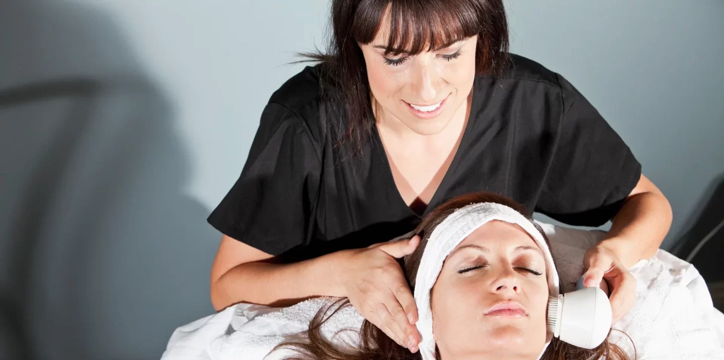 Aesthetician doing facial cleansing to a woman client at medical spa