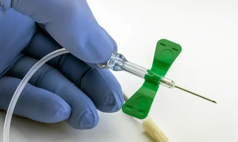 a portrait of a hand of a medical provider holding a butterfly needle