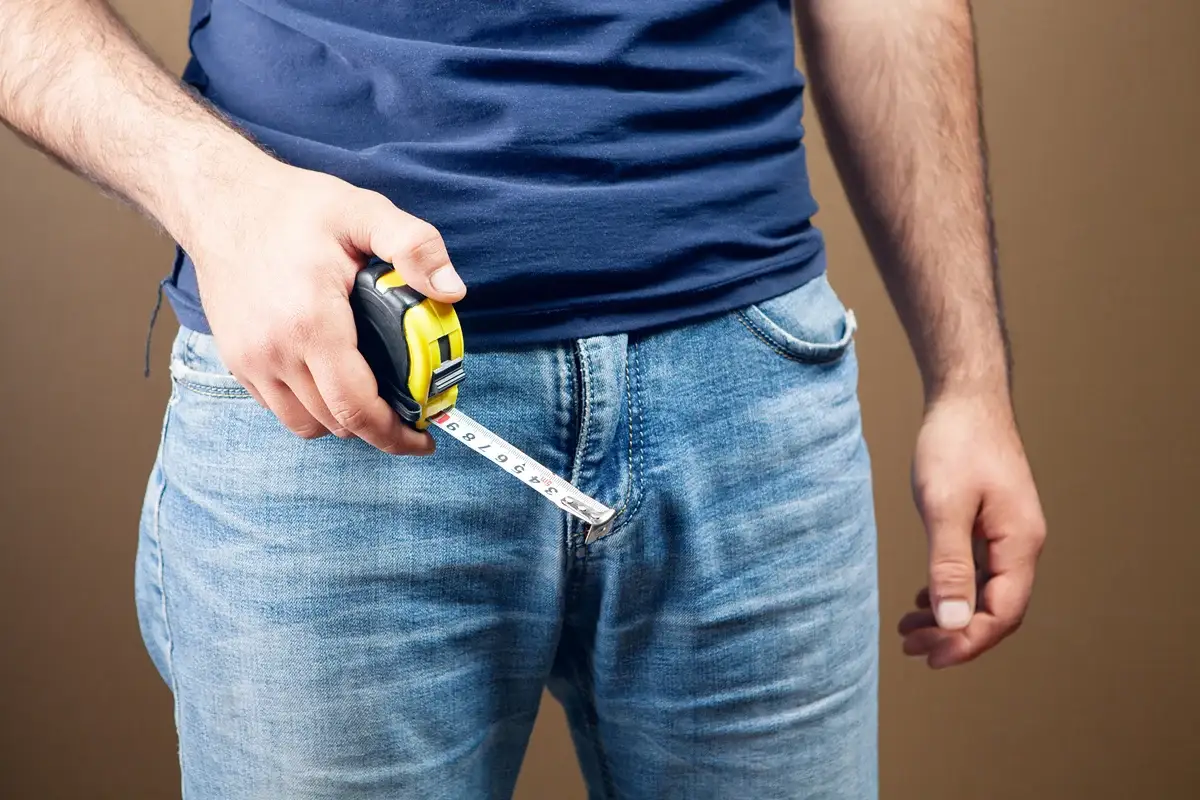 A man holding a centimeter in his hands and measures a penis.