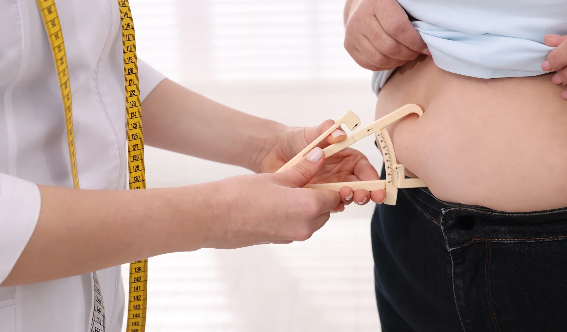 healthcare practitioner measures fat on the patient's belly