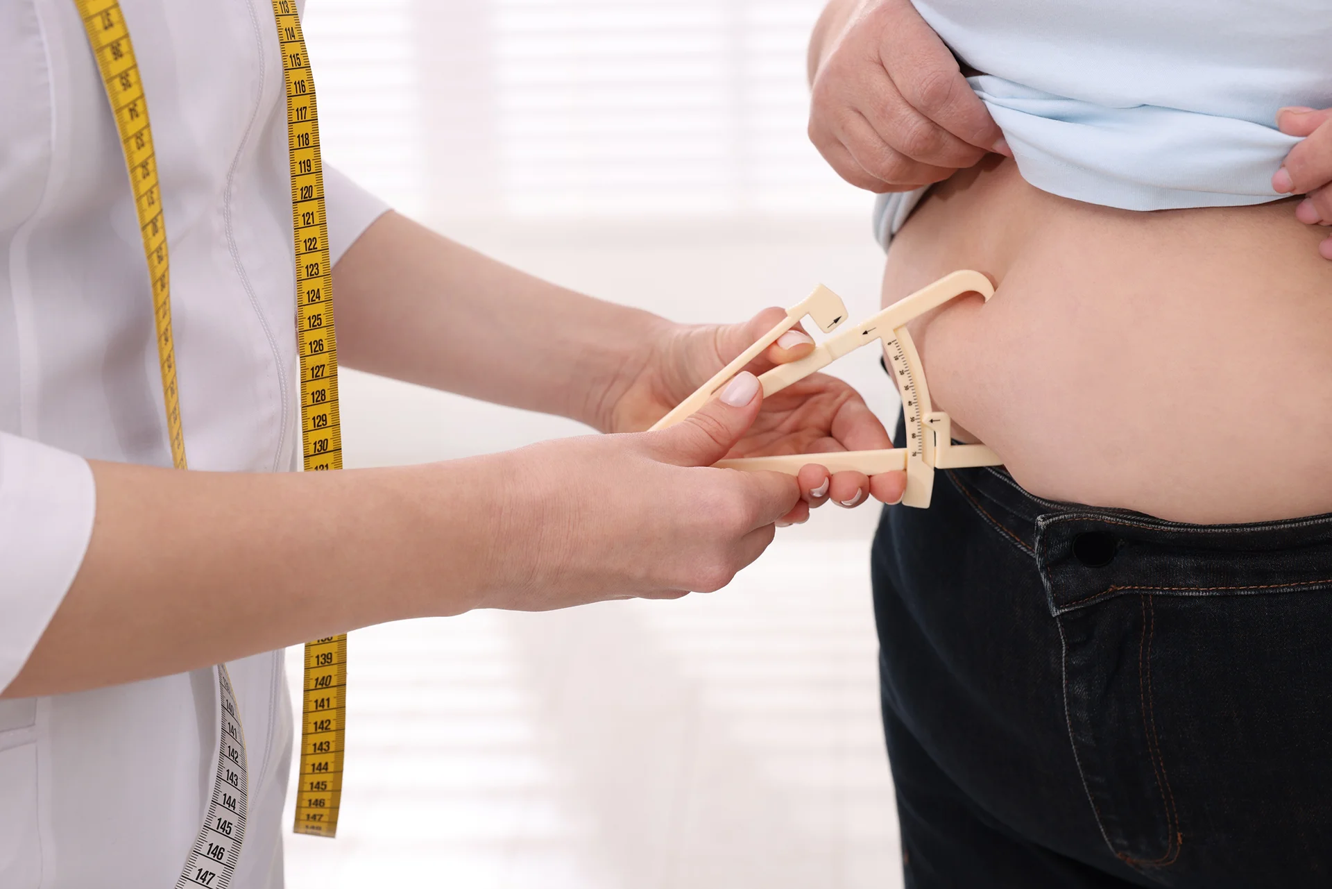healthcare practitioner measures fat on the patient's belly